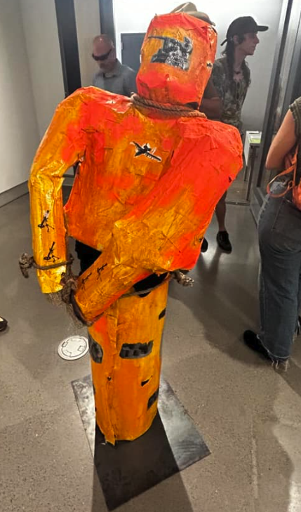 Sculpture of an orange and red suit with handcuffs