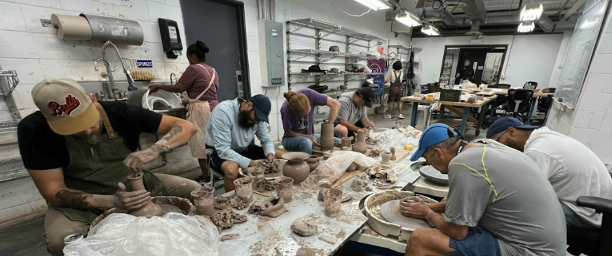 Veterans around a table, bent over and working with clay