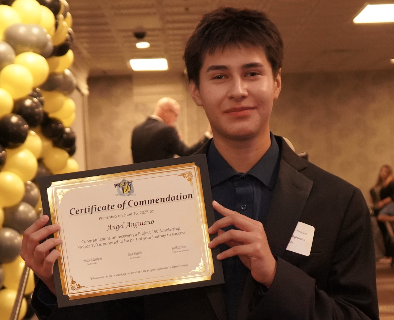 Young man holding up a certificate in a banquet hall