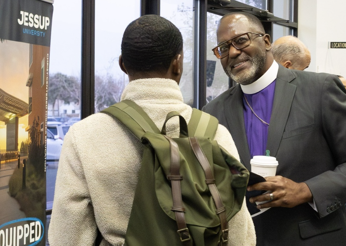 Man in a clerical collar talking to a student