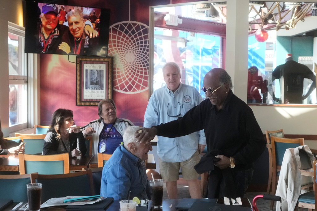 Tom Henschel, bottom, is greeted by Gregory Eaton, right, friends who have attended every Super Bowl football game