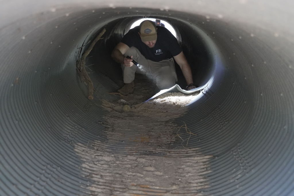 An investigator looks inside a culvert in the neighborhood where Annie Guthrie, whose mother Nancy Guthrie has been missing for more than a week