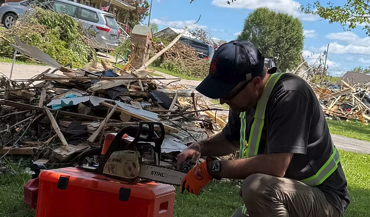 Man near a pile of rubble and a chainsaw sharpener