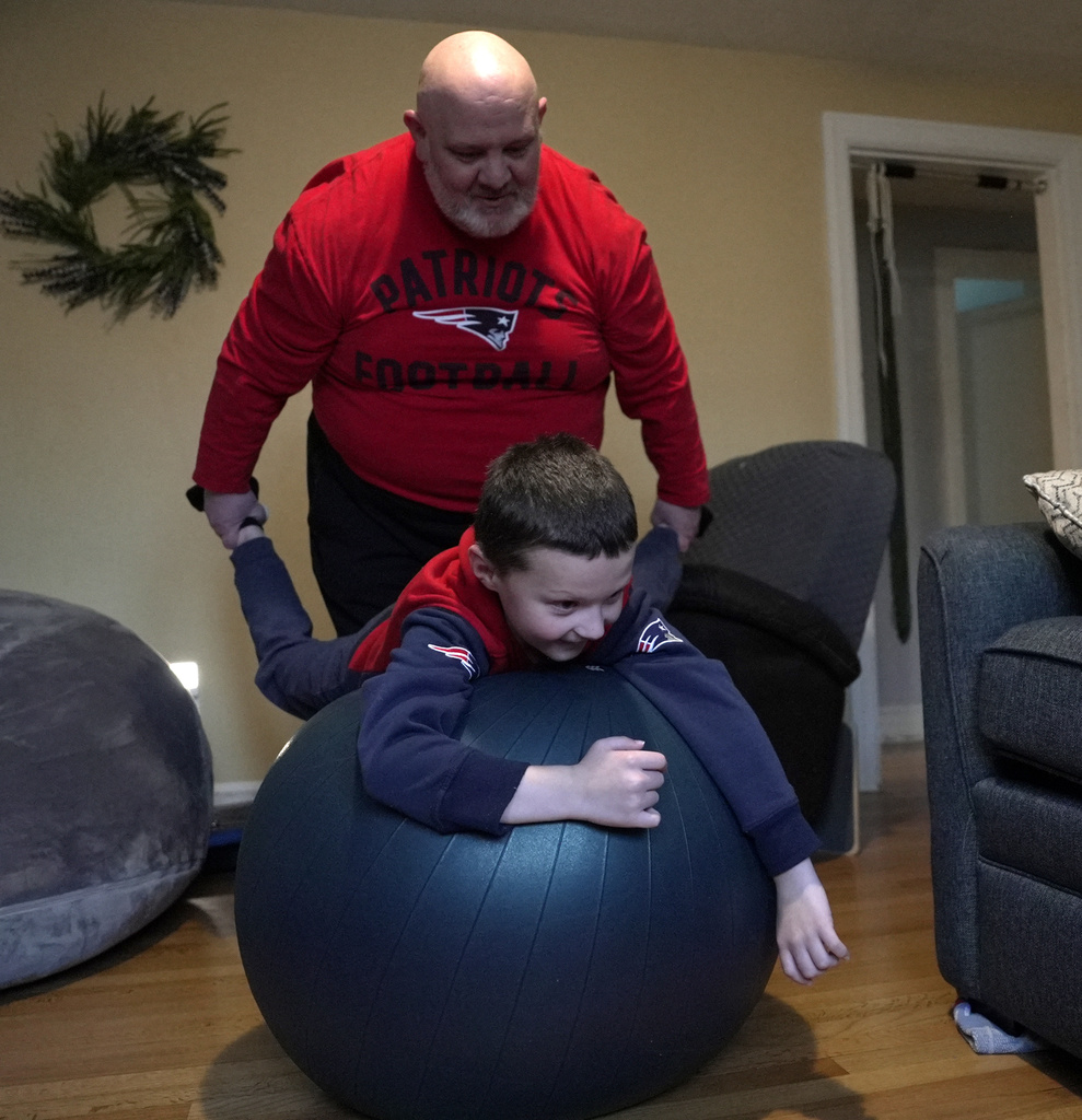 Matthew Murphy plays with his son, Connor, on a balance ball at home
