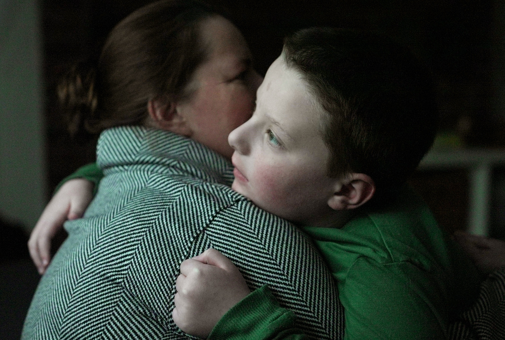 Ronan Murphy hugs his mother, Andrea, while looking at the snow falling outside their home
