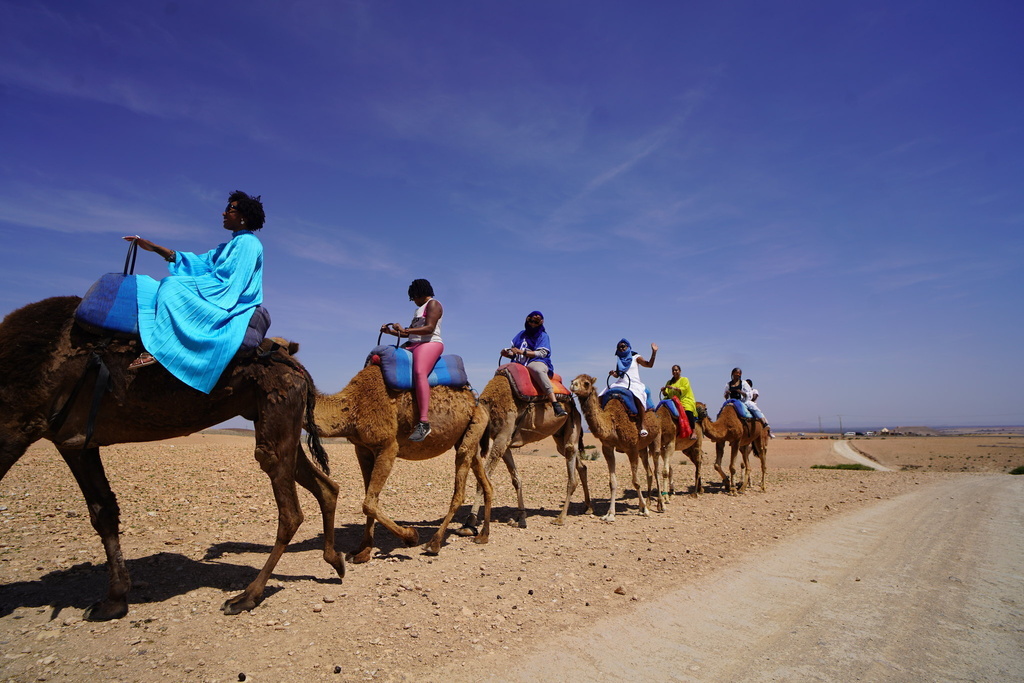 Roshida Dowe, foreground, rides a camel accompanied by several participants of the ExodUS Summit, an event business she co-leads to help Black women take career breaks and move abroad. 