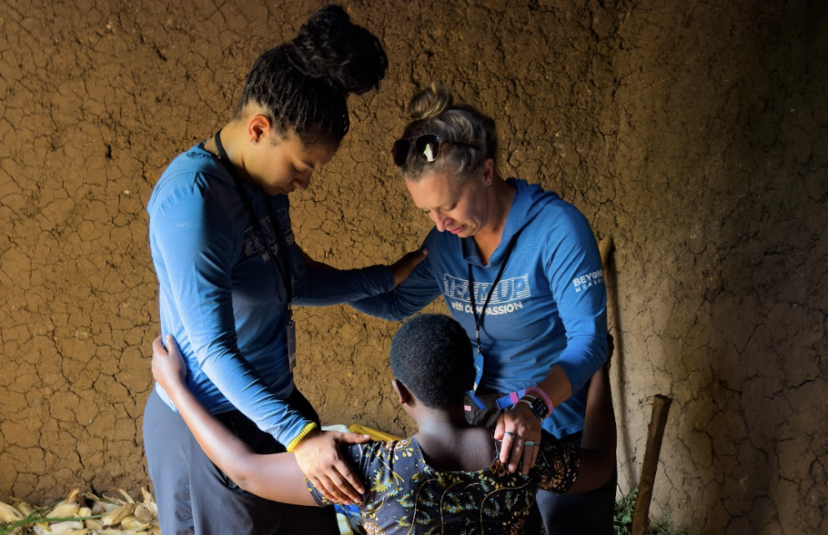 Three women praying in a mud hut
