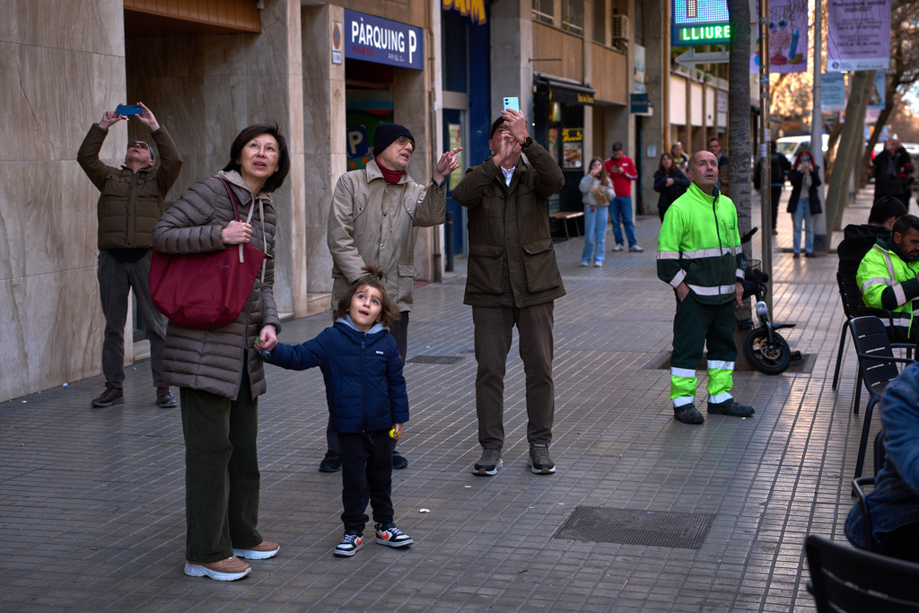 People watch as a crane lifts the upper arm of the cross onto the Tower of Jesus Christ at the Sagrada Familia in Barcelona, Spain