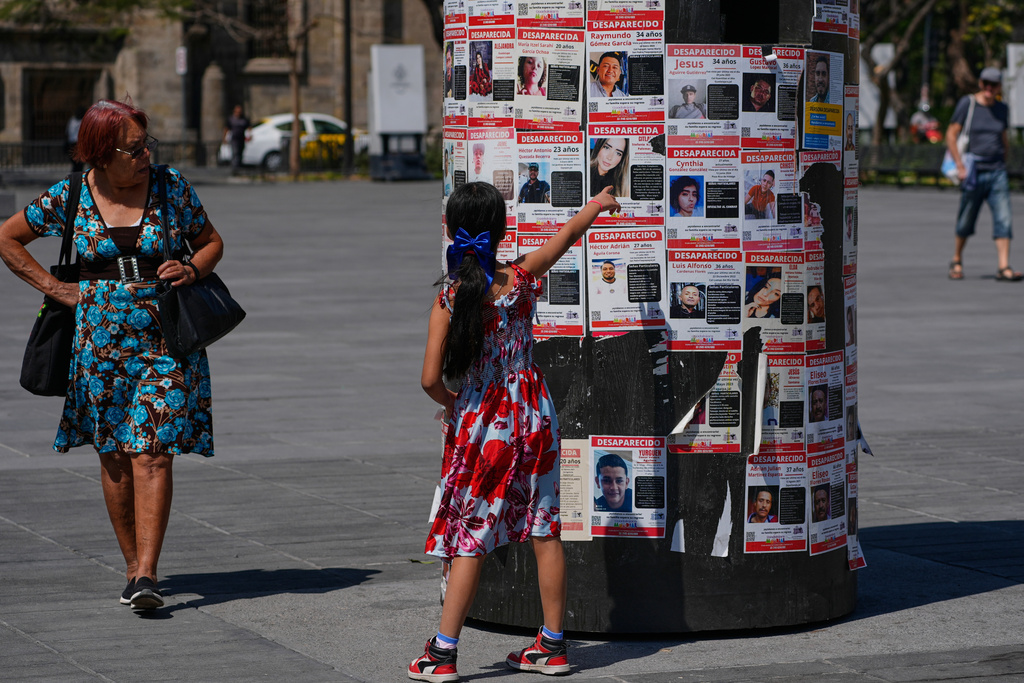 A girl points at posters bearing the faces of missing persons in Guadalajara, Mexico.