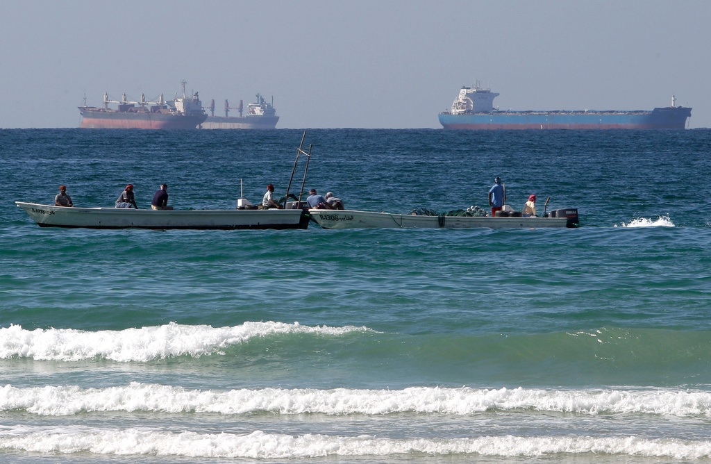 Fishermen work in front of oil tankers south of the Strait of Hormuz offshore the town of Ras Al Khaimah in United Arab Emirates