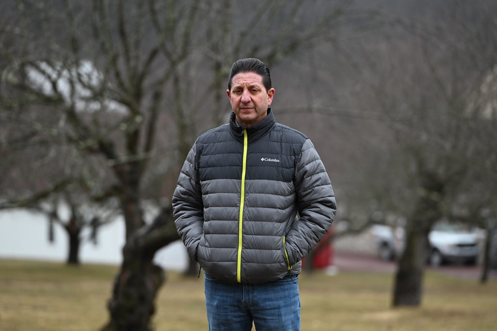 John Zola stands in an apple tree grove on his property on a spot where he says the local electric utility wants to build a 500-kilovolt line across his land