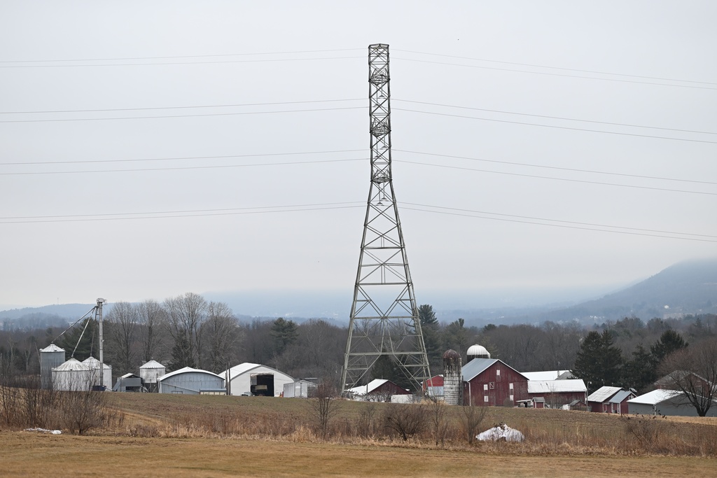 A 235-kilovolt power line towers over farm buildings near where the local power utility plans to build a 500-kilovolt power line on towers as tall as 240 feet
