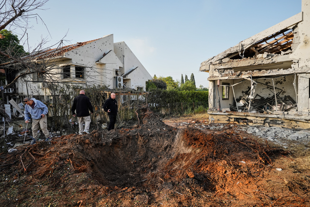People inspect homes damaged by a projectile launched from Lebanon, in Haniel central Israel
