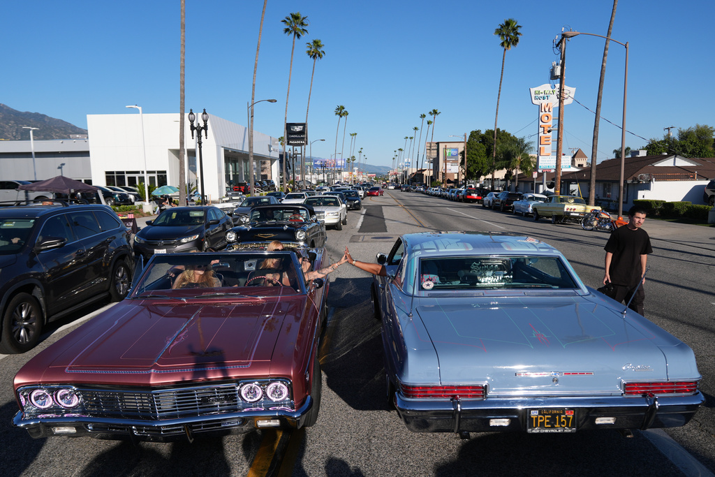 Sandy Avila, left, driving a 1966 Chevy Impala SS, high-fives a fellow lowrider at the 6th Annual Lady Lowrider Cruise Night in celebration of International Women