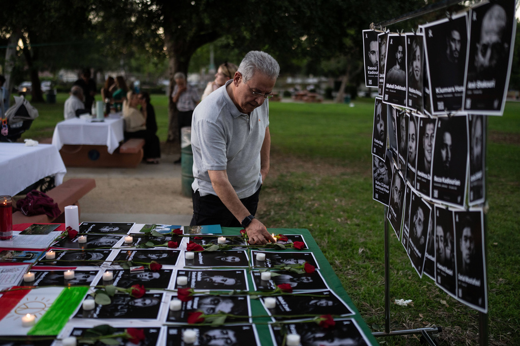 Geev Lameh places a candle by photos described as Iranian protesters killed in January, during a community gathering ahead of the Nowruz holiday in the Encino neighborhood of Los Angeles
