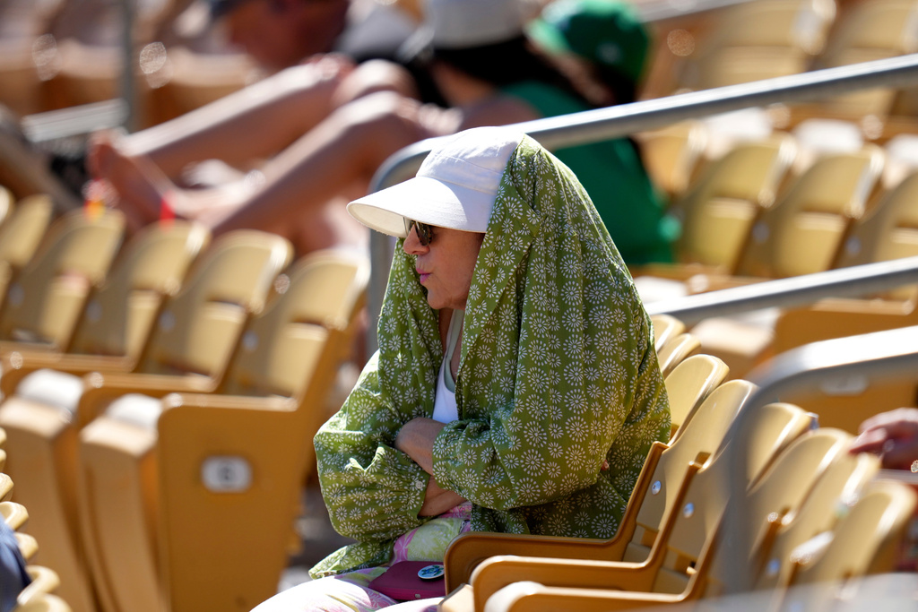 baseball fan tries to shield from the sun during the fourth inning of a spring training baseball game between the Chicago White Sox and the Athletics, Tuesday, March 17, 2026, in Phoenix.