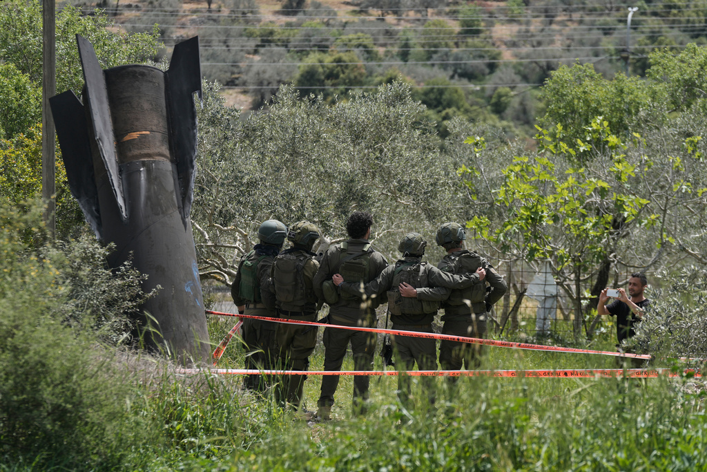 Israeli soldiers take their photo beside the wreckage of an Iranian missile that landed in the West Bank village of Kifl Haris