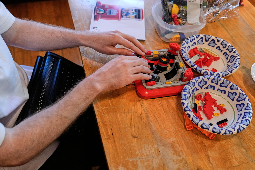 Matthew Shifrin, the founder of Bricks for the Blind, feels for specific pieces while building a LEGO gum ball machine 
