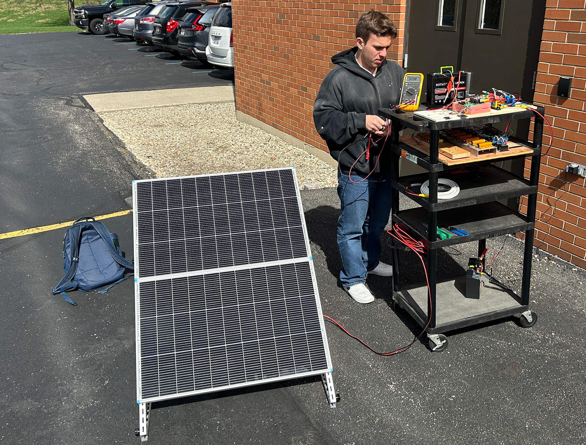 Cedarville University senior Joshua Wassei checks a prototype solar charge controller during outdoor testing