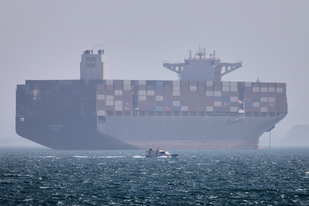 A container ship sits at anchor as a small motorboat passes in the foreground in the Strait of Hormuz off Bandar Abbas, Iran