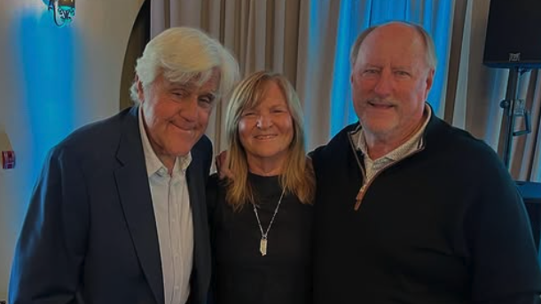 Grey-haired man with woman in between another man with a mustache