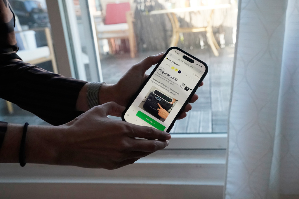 Sonam Velani shows an app that is used to plug in a battery from Every Electric to power an air conditioner