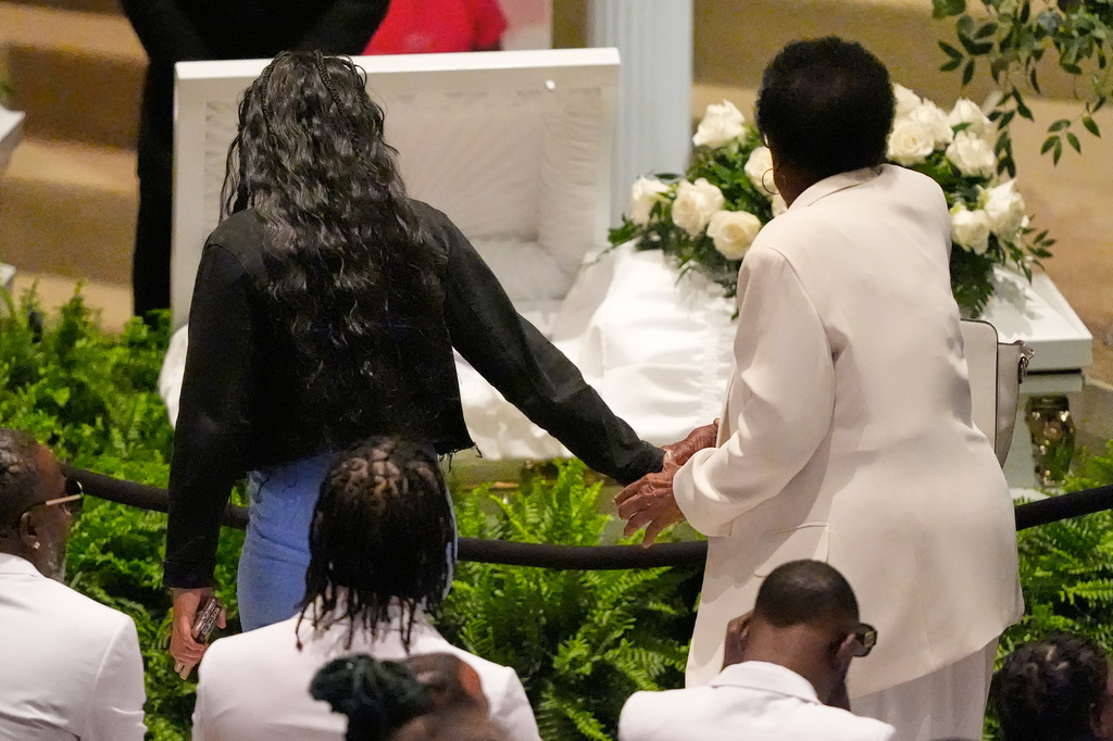 Mourners walk by caskets for the eight children 