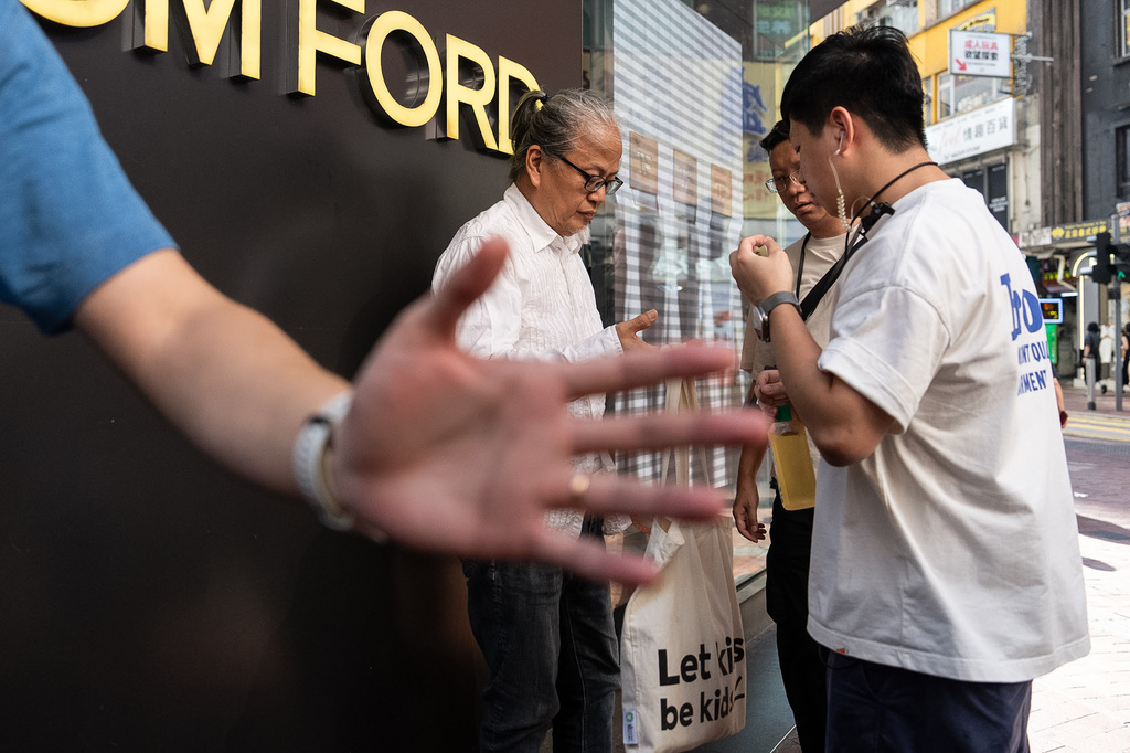 Police officers stop and search artist Sanmu Chen in the Causeway Bay area on the eve of the 37th anniversary of China