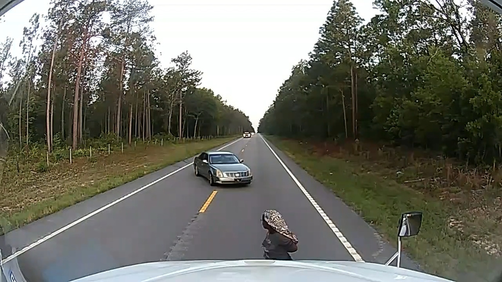 Frame grab from a dashboard camera video, a cuffed woman is seen running away from her alleged kidnapper near Aiken, S.C.