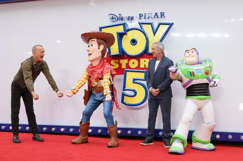 Tom Hanks, left, and Tim Allen pose for photographers with people costumed as the characters Woody and Buzz Lightyear upon arrival at a launch event for the film
