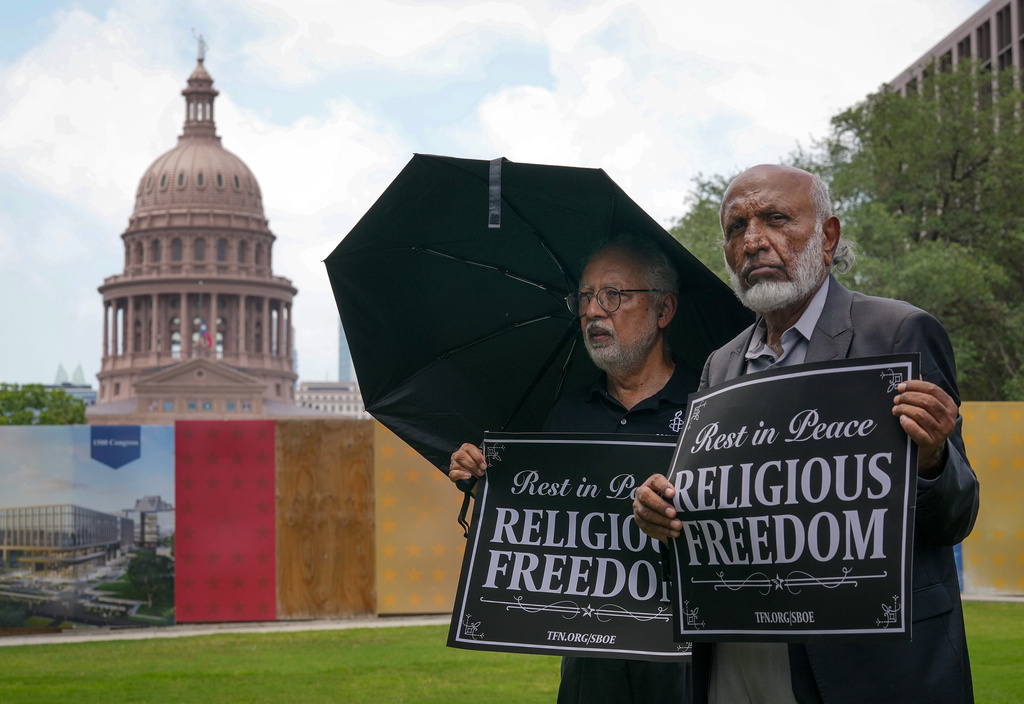 Mohammed Nasrullah, left, and Aziz Soomro, both of Houston, participate in an interfaith funeral-themed protest outside the Barbara Jordan Building in Austin 