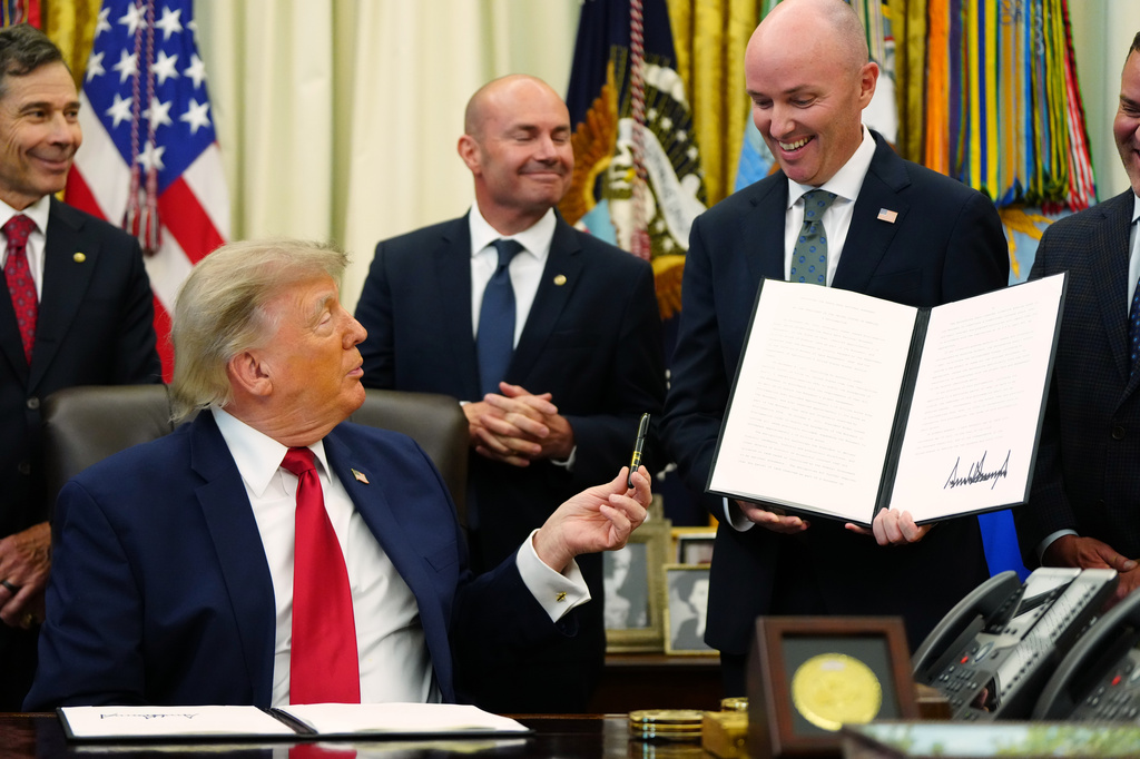 President Donald Trump hands a pen to Utah Gov. Spencer Cox after signing executive orders modifying the Grand Staircase-Escalante National Monument and the Bears Ears National Monument in the Oval Office