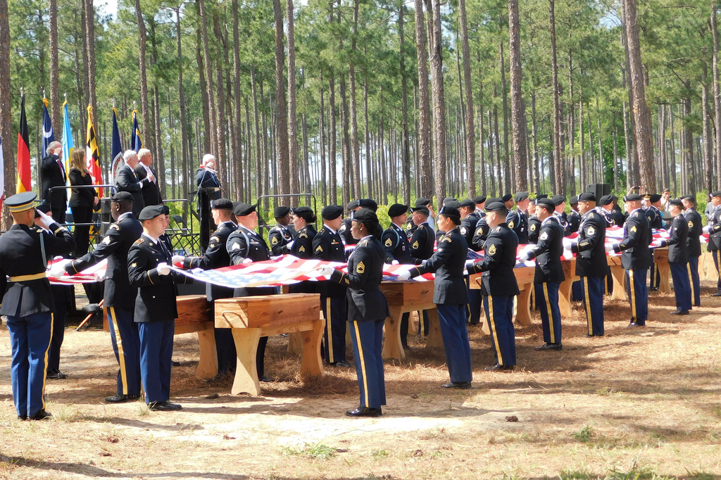 Military personnel fold flags for the remains of 12 Continental soldiers killed at the Battle of Camden, S.C., during a memorial ceremony on April 22, 2023