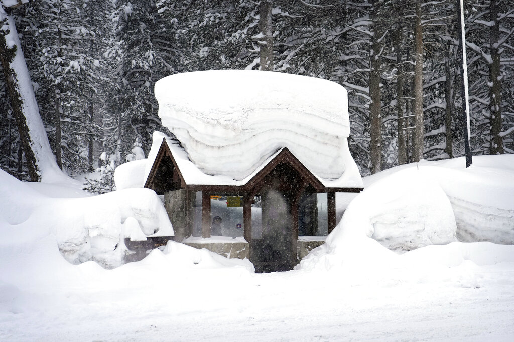 A person sits in a snow-covered bus stop Friday, Feb. 24, 2023, in Olympic Valley, Calif. California and other parts of the West are facing heavy snow and rain from the latest winter storm to pound the United States.