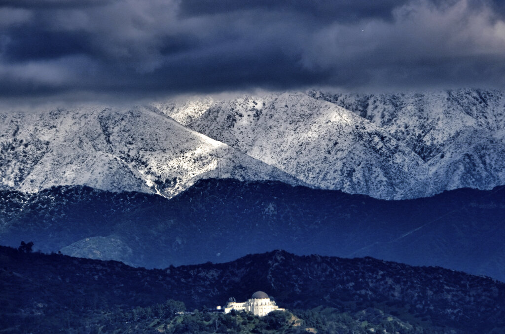 Storm clouds and snow are seen over the San Gabriel mountain range behind Griffith Observatory in the Hollywood Hills part of Los Angeles 