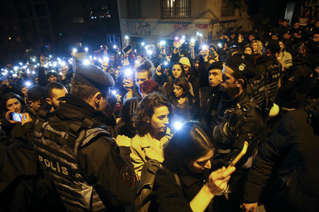 Protesters walk past a police security line as they gather to mark the International Women