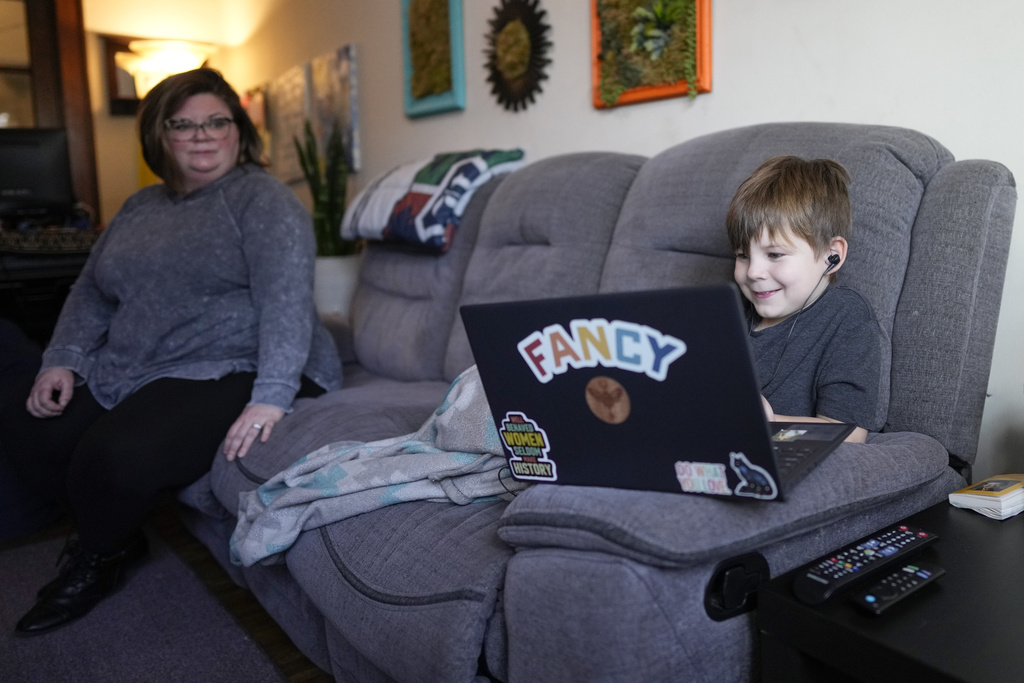 Jessica Blalack, left, watches as her son Phoenix Blalack, 6 , works with a tutor on his laptop in his Indianapolis home