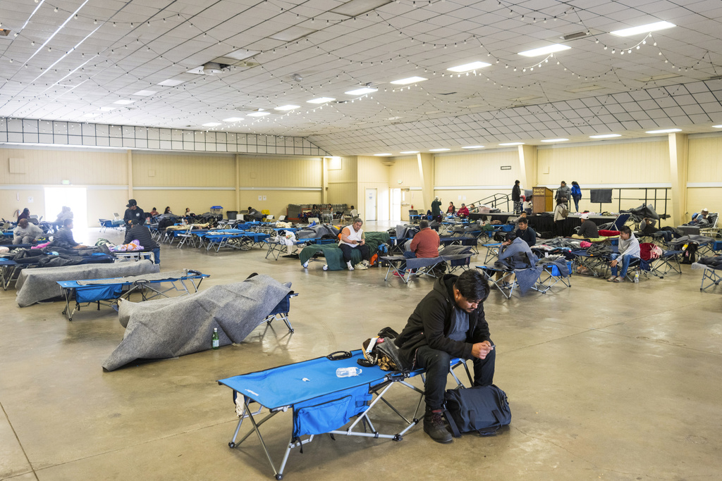 People rest at an evacuation center at Santa Cruz County fairgrounds in Watsonville, Calif.