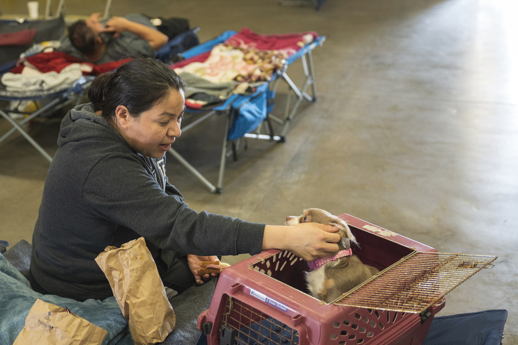 Anais Rodriguez comforts her dog, Mile, at an evacuation center at Santa Cruz County fairgrounds in Watsonville, Calif.