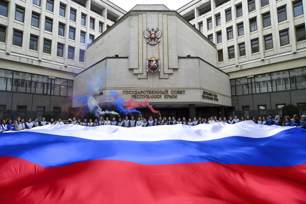 People hold a Russian national flag in front of the Crimean parliament 
