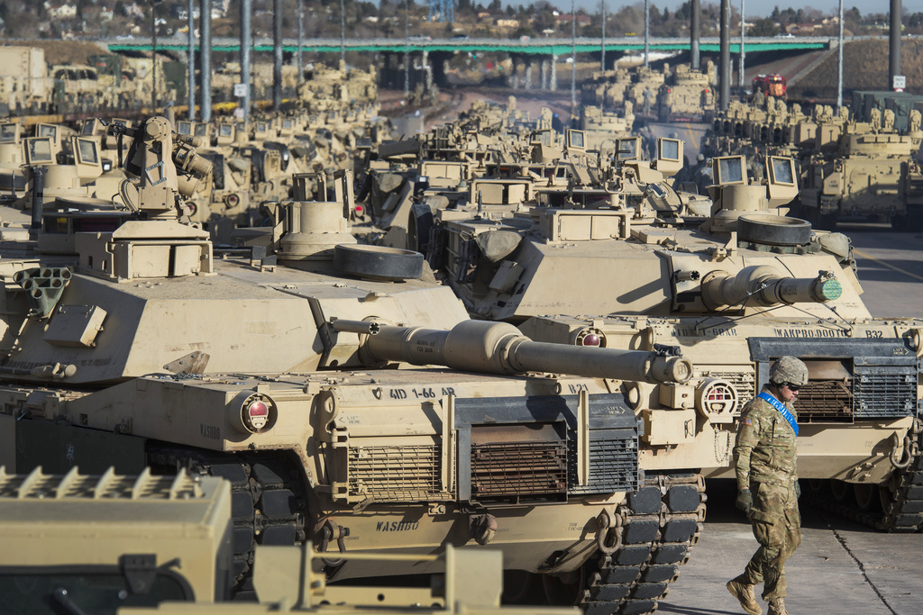 A soldier walks past a line of M1 Abrams tanks
