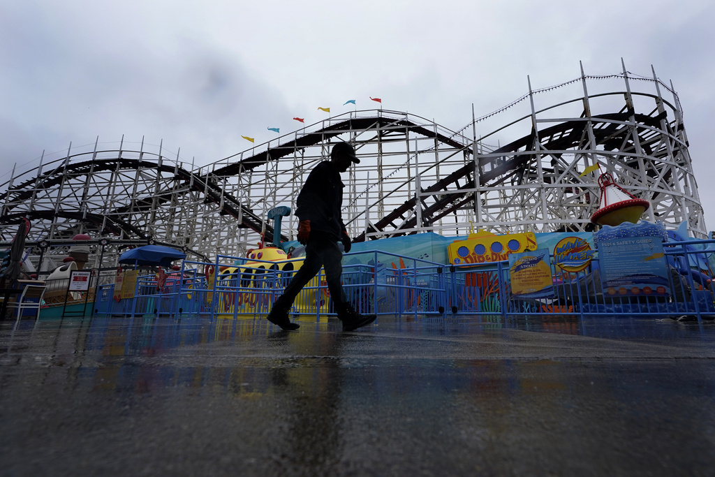 A worker passes the roller coaster at Belmont Park as rain engulfs the area in San Diego.