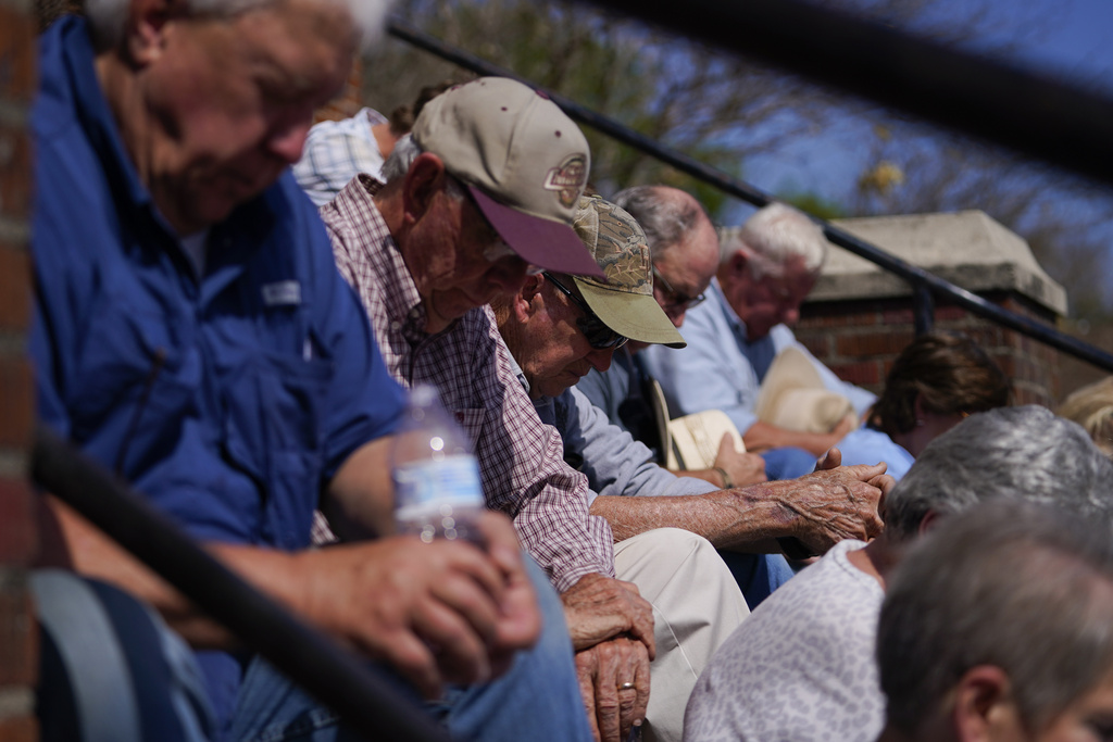 People sit and pray on the steps of the Rolling Fork United Methodist Church