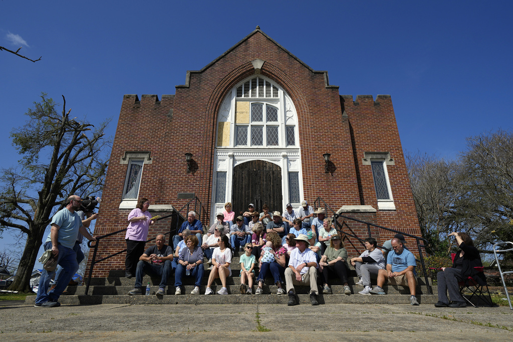 People sit and pray on the steps of the Rolling Fork United Methodist Church while worshiping, Sunday, March 26, 2023, in Rolling Fork, Miss.