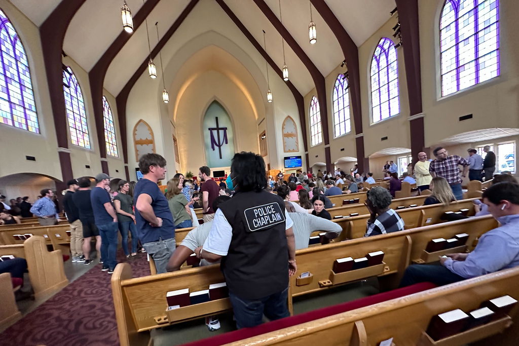 A police chaplain stands by as children from The Covenant School, a private Christian school in Nashville, Tenn., are taken to a reunification site at the Woodmont Baptist Church 