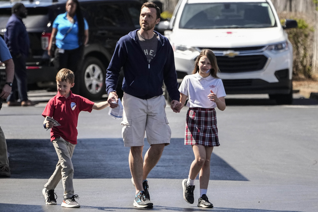 A man walks with children at the Woodmont Baptist Church after a school shooting at The Covenant School