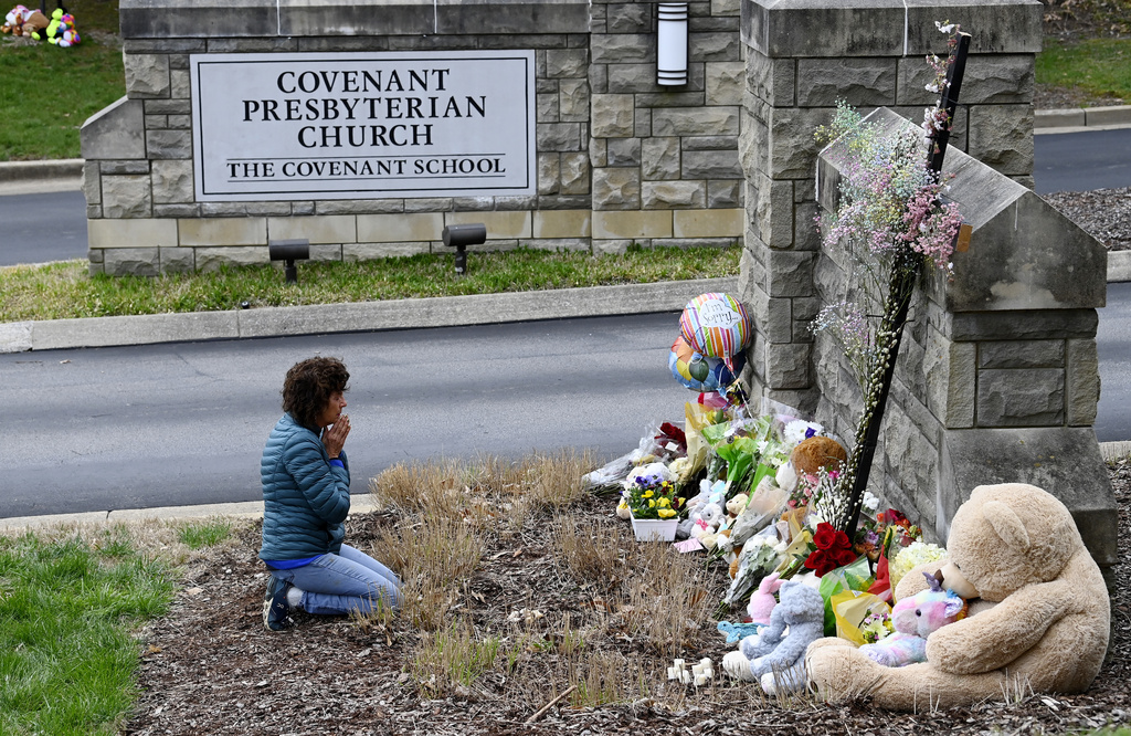 Robin Wolfeden prays in front of a makeshift memorial at the entrance to The Covenant School