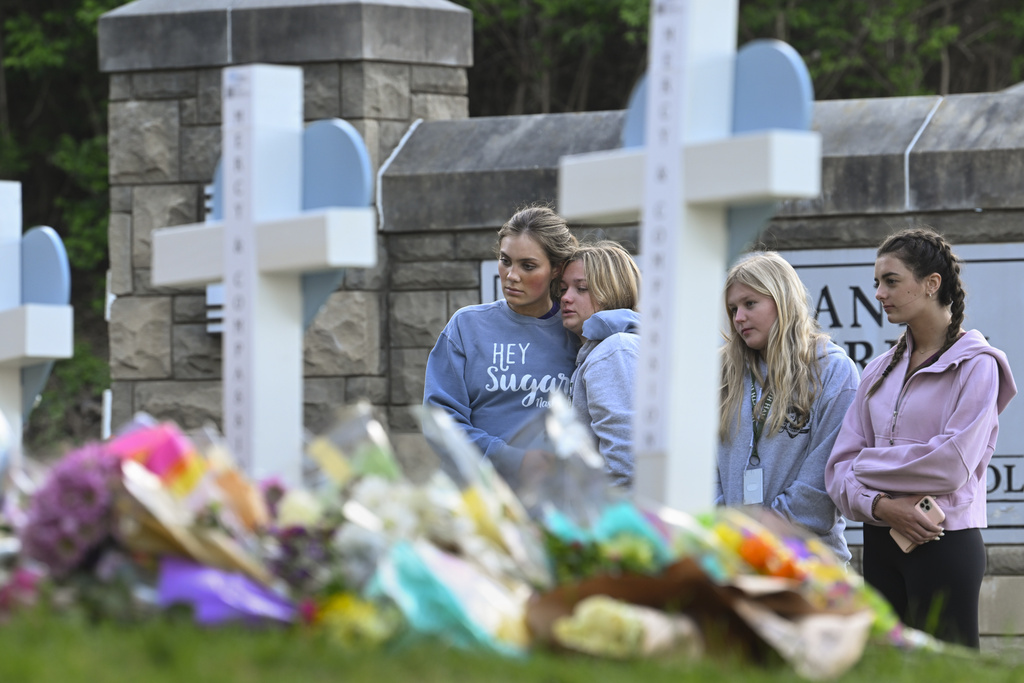 Students at a nearby school pay respects at a memorial for the people who were killed, at an entry to Covenant School