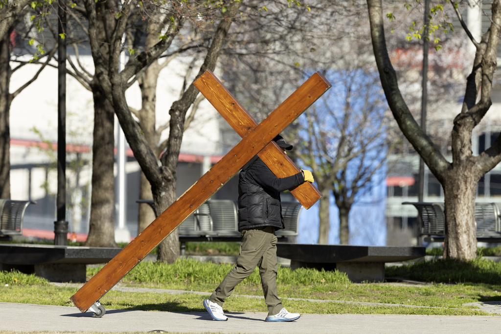 Dan Beazley from Michigan walks with a cross before a vigil held for victims of The Covenant School shooting