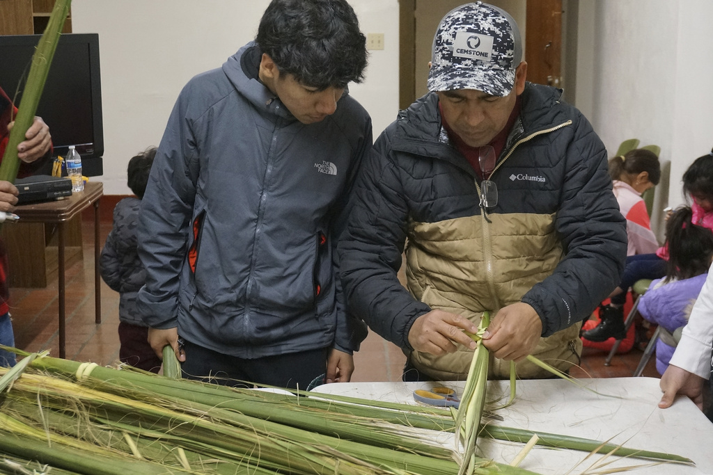 Reynaldo Hidalgo, right, teaches a volunteer how to weave palm fronds at the Church of the Incarnation in Minneapolis